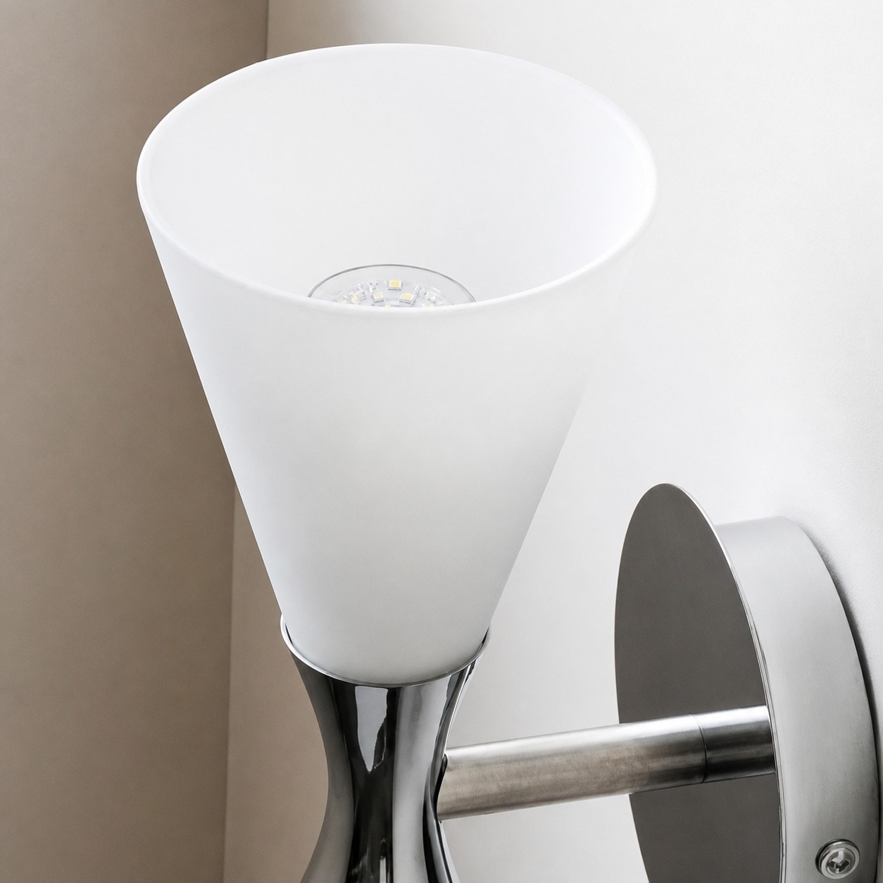 White glass shade and socket detail on chrome wall sconce