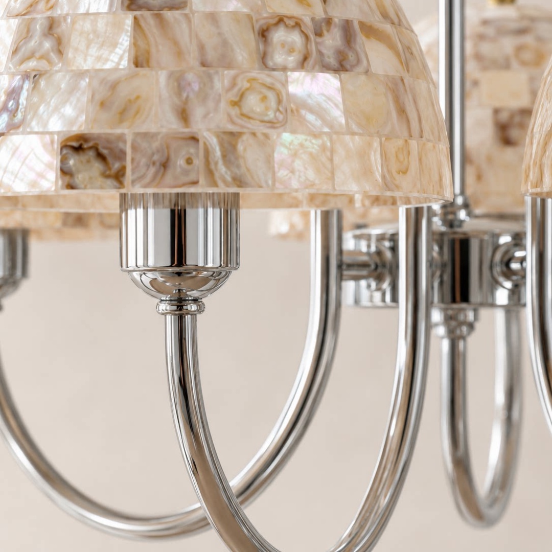 Close view of beige shell mosaic shades and polished metal chandelier arms
